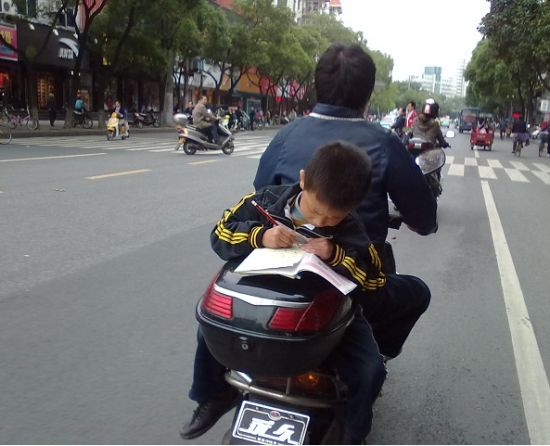 图文:孝感小学生摩托车上赶作业 引网友心酸